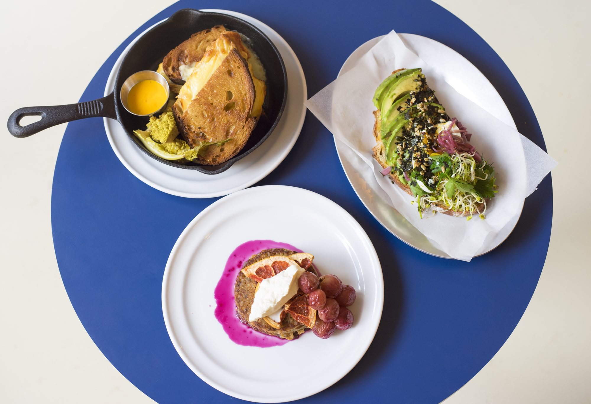 Grilled cheese, avocado toast et pancakes servis sur la table bleue d'Echo